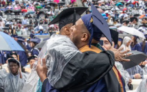 Two male graduates share a hug.