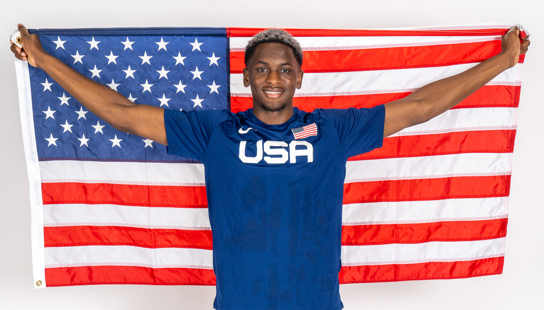 A young male athlete triumphantly holds up the American flag.