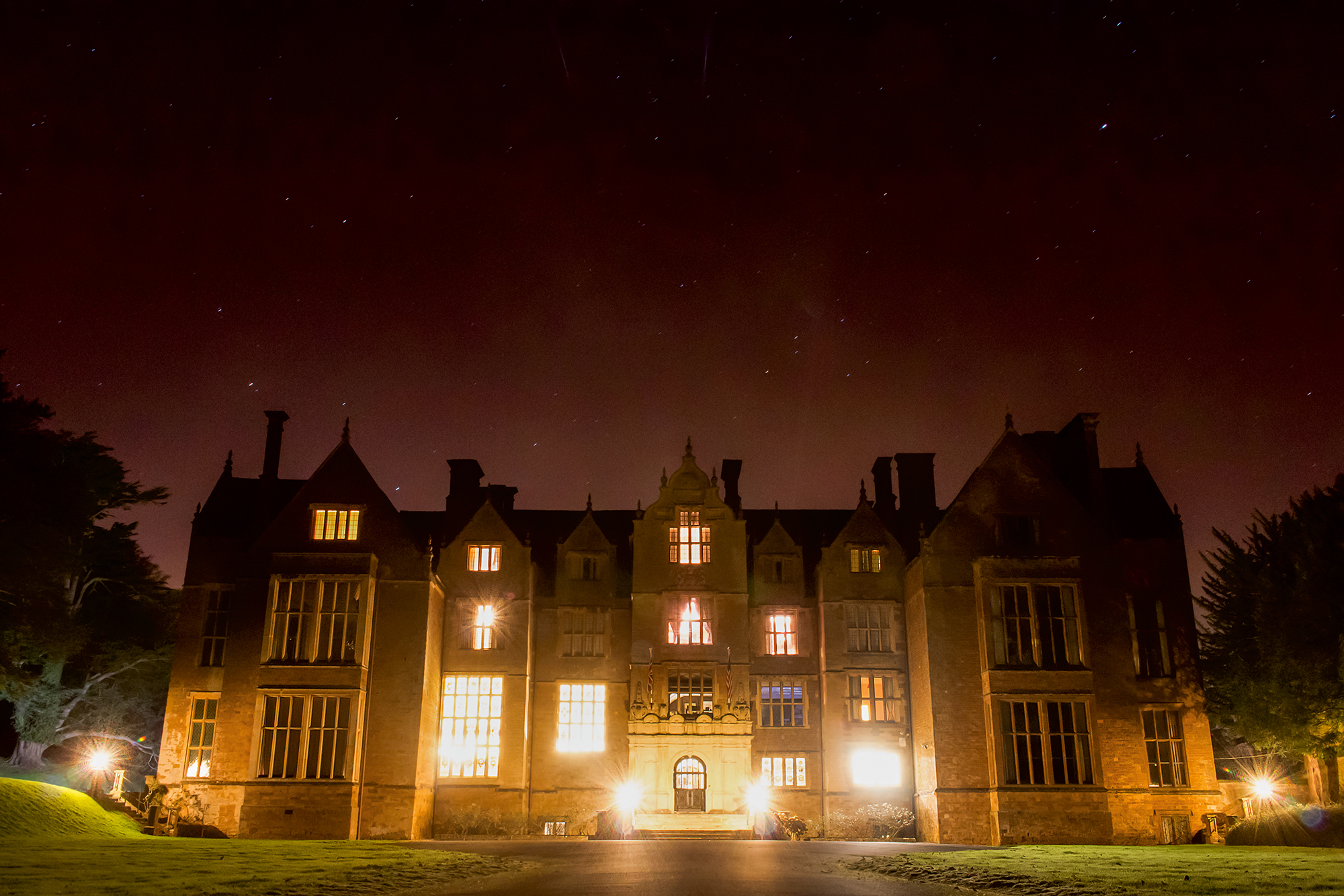 Wroxton Abbey with windows alight at night.