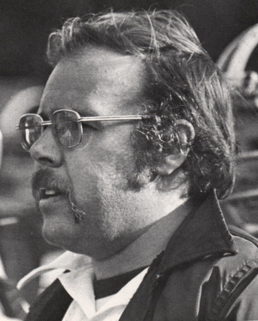 a close-up shot on a man. he wears glasses and looks at something to the side. the photo is in black and white.