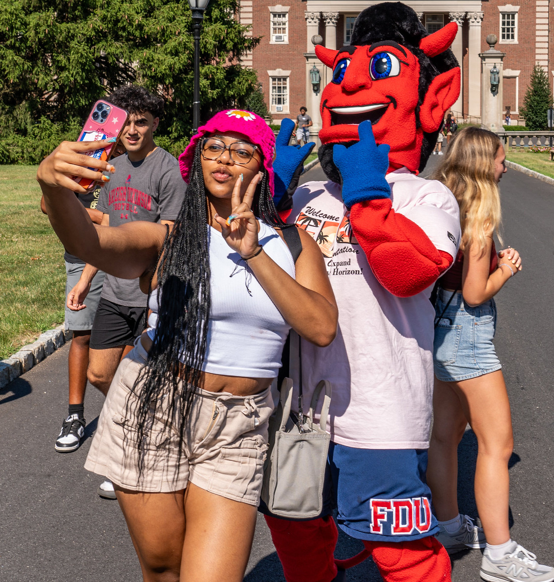 A student throws up a peace sign and takes a selfie with Ian the Devil.