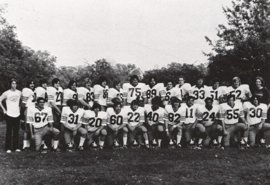 A football team in uniform poses on the football field. the photo is in black and white.