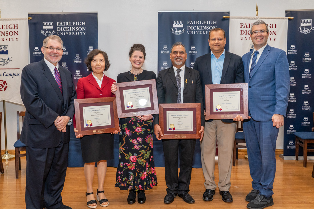 Four faculty members hold up their awards and are flanked by two administrators.