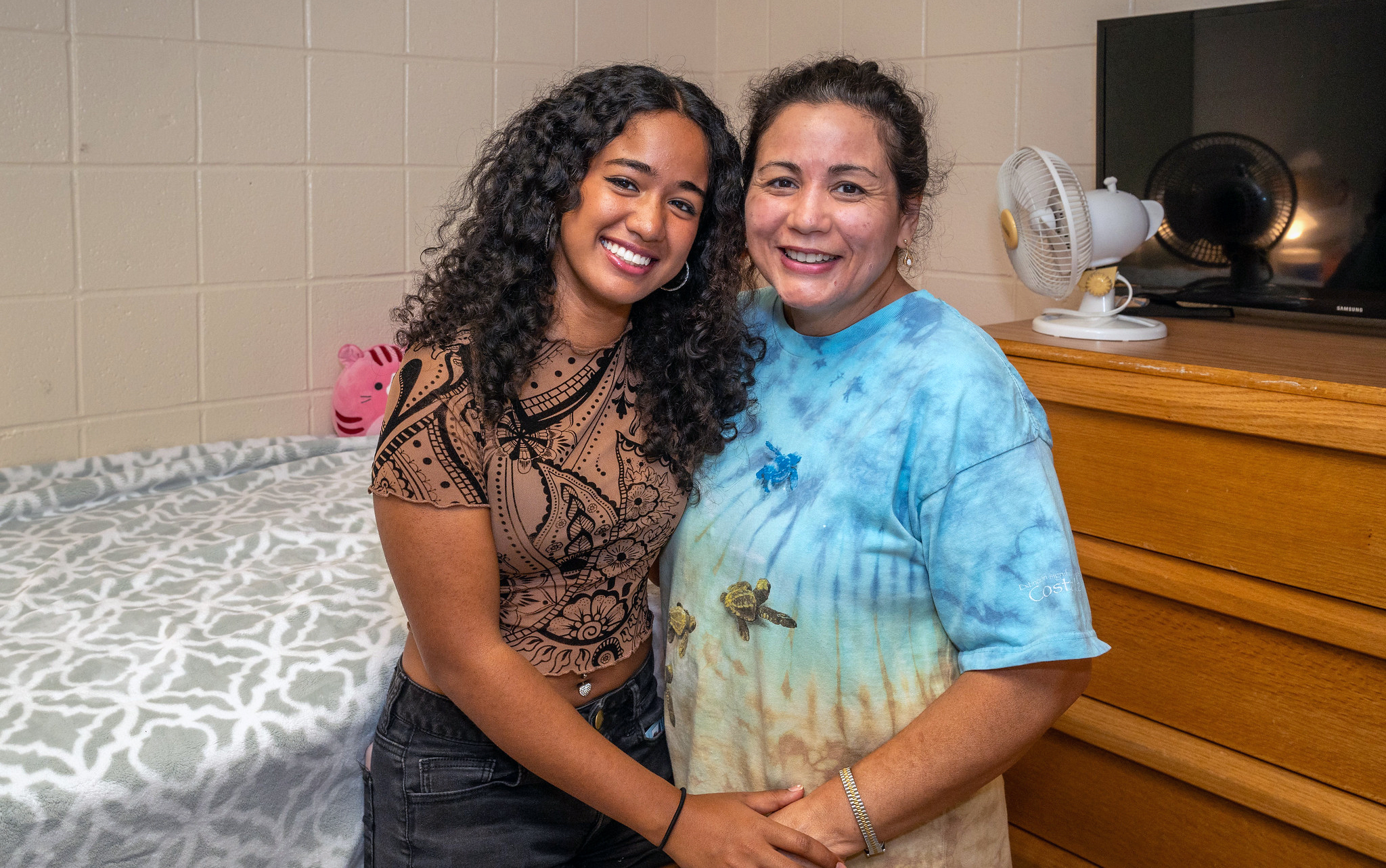 Two people share a hug in a dorm room.