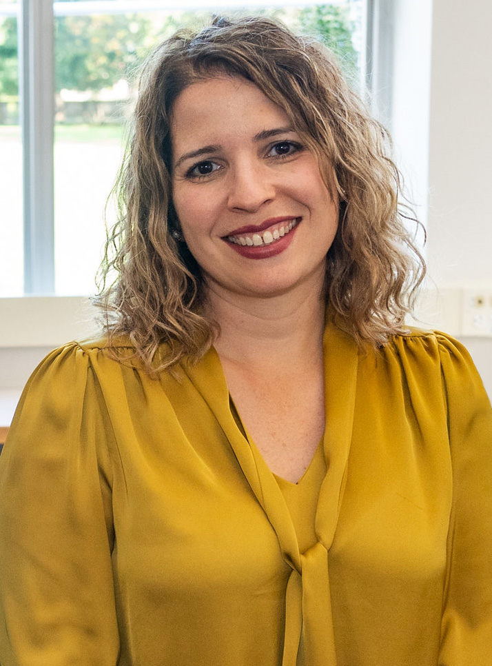 A woman in a yellow blouse smiles for a photo.