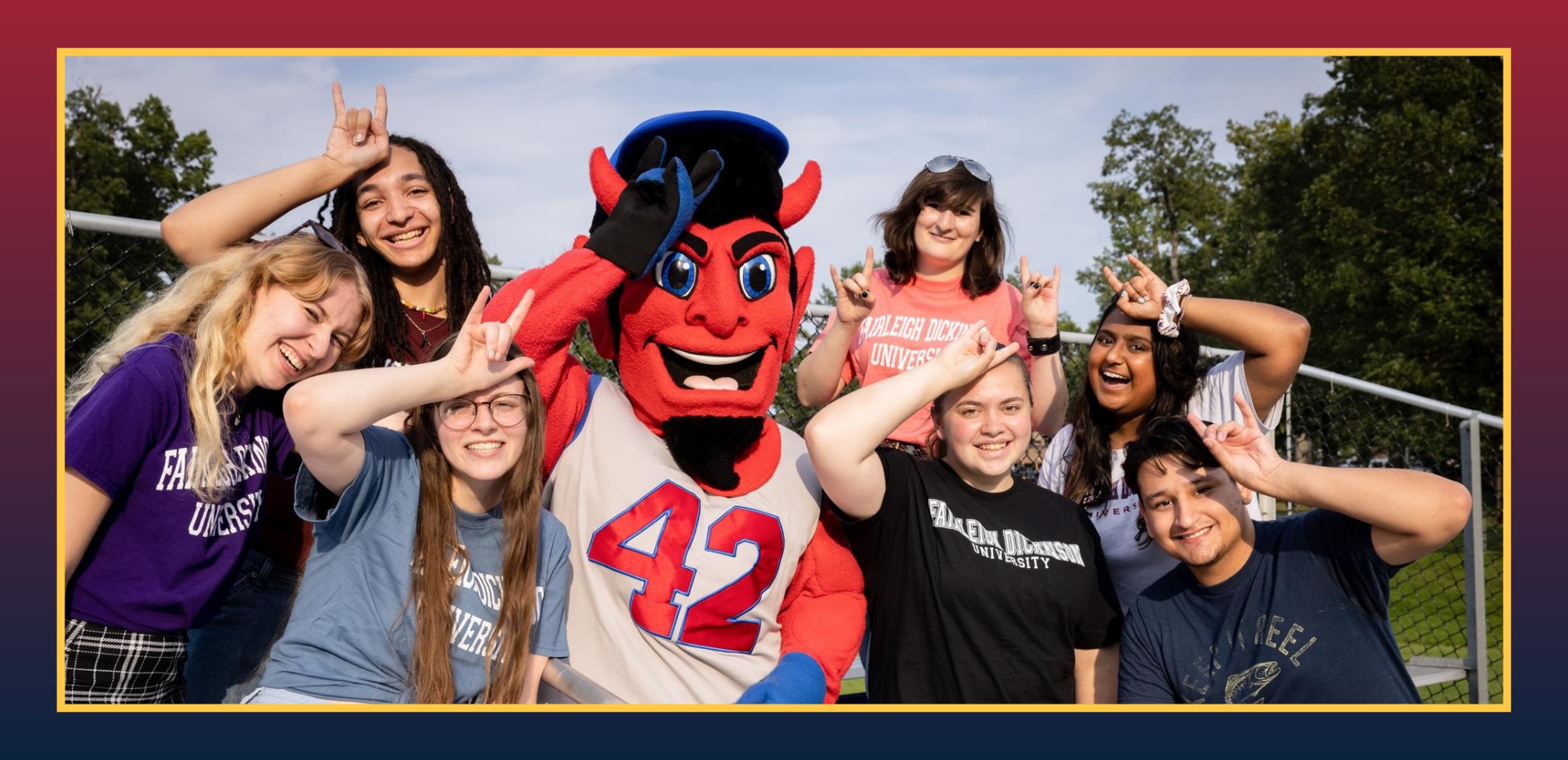 students and the Ian the Devil mascot smile for the camera. they hold on horns hand signals.