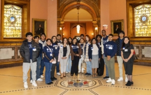 A group of students pose for a photo at the state capitol. they wear shirts that read "FDU Hispanic Center."