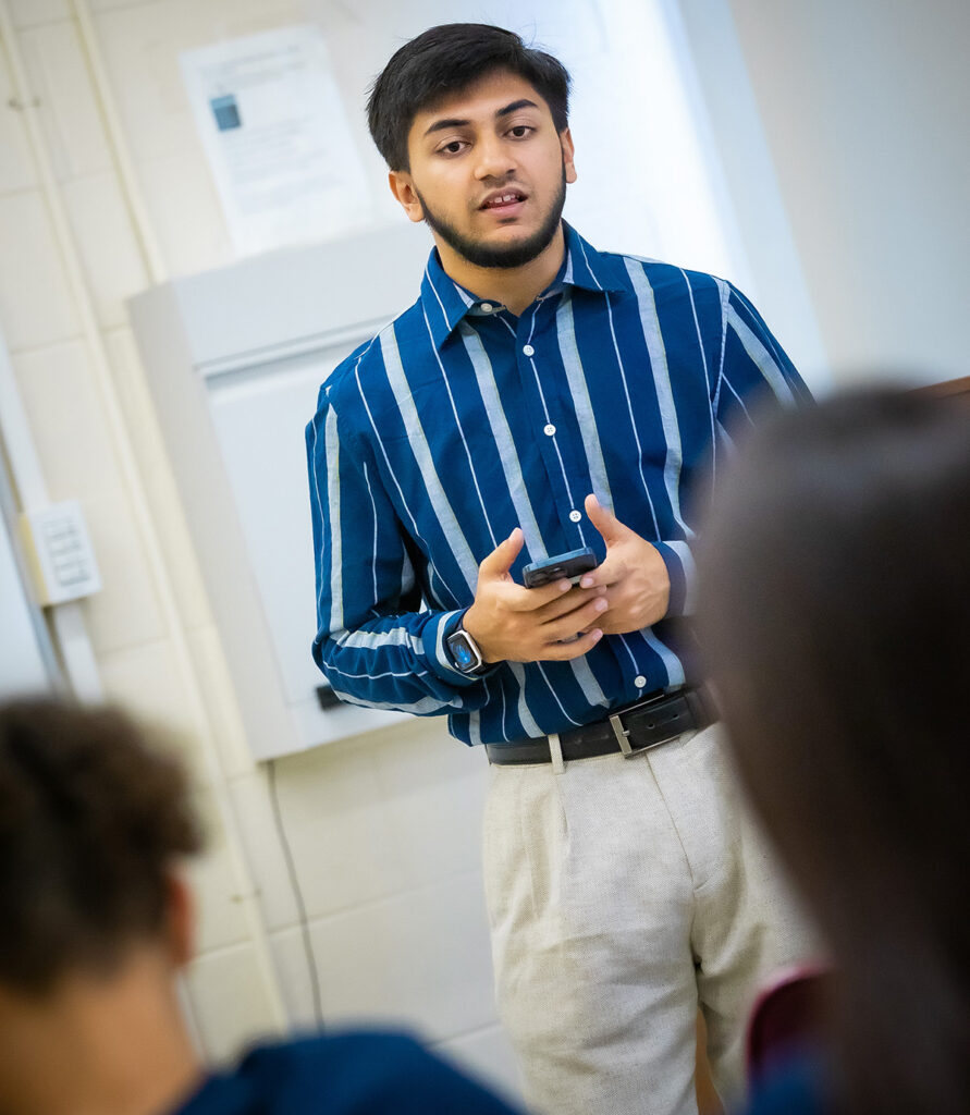 A male college student addresses a group of middle school students.