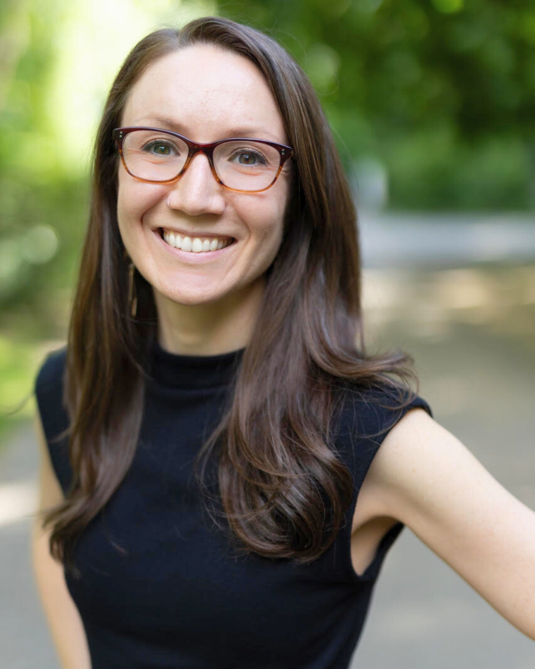 portrait of a woman outside. she wears glasses and a black top.