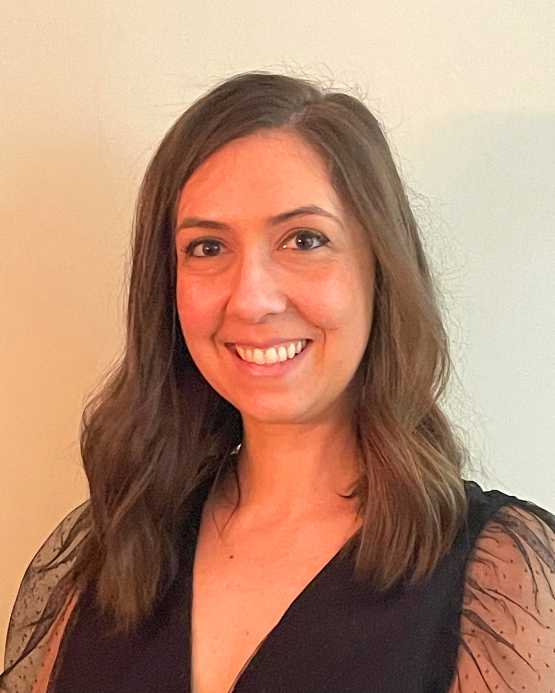 portrait of a woman against a wall. she wears a black top.