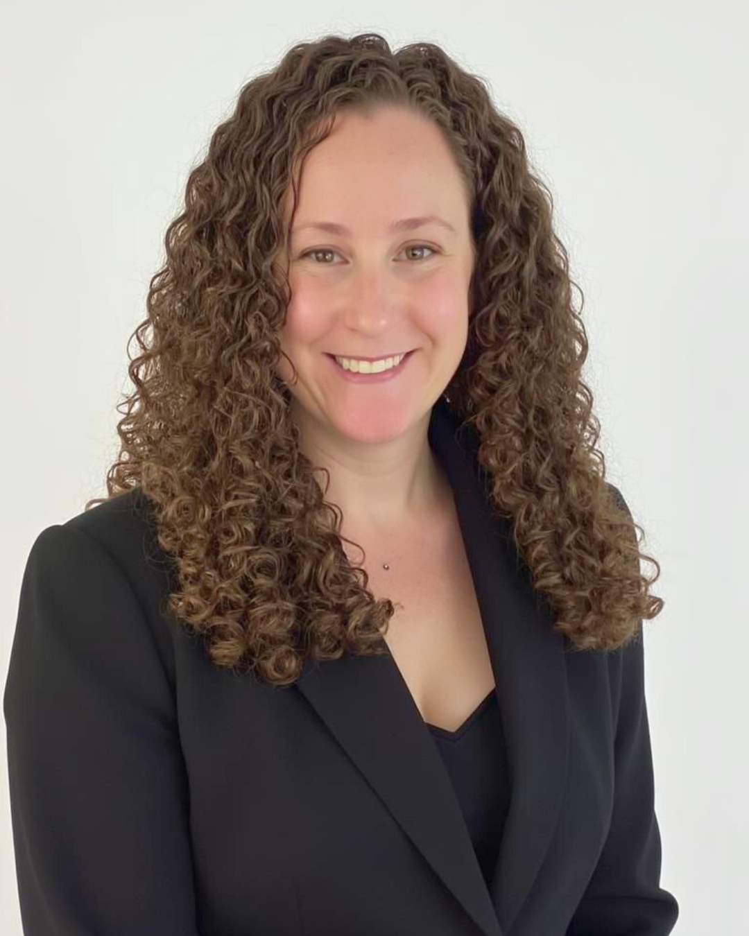 portrait of a woman against a wall. she wears a black blazer.