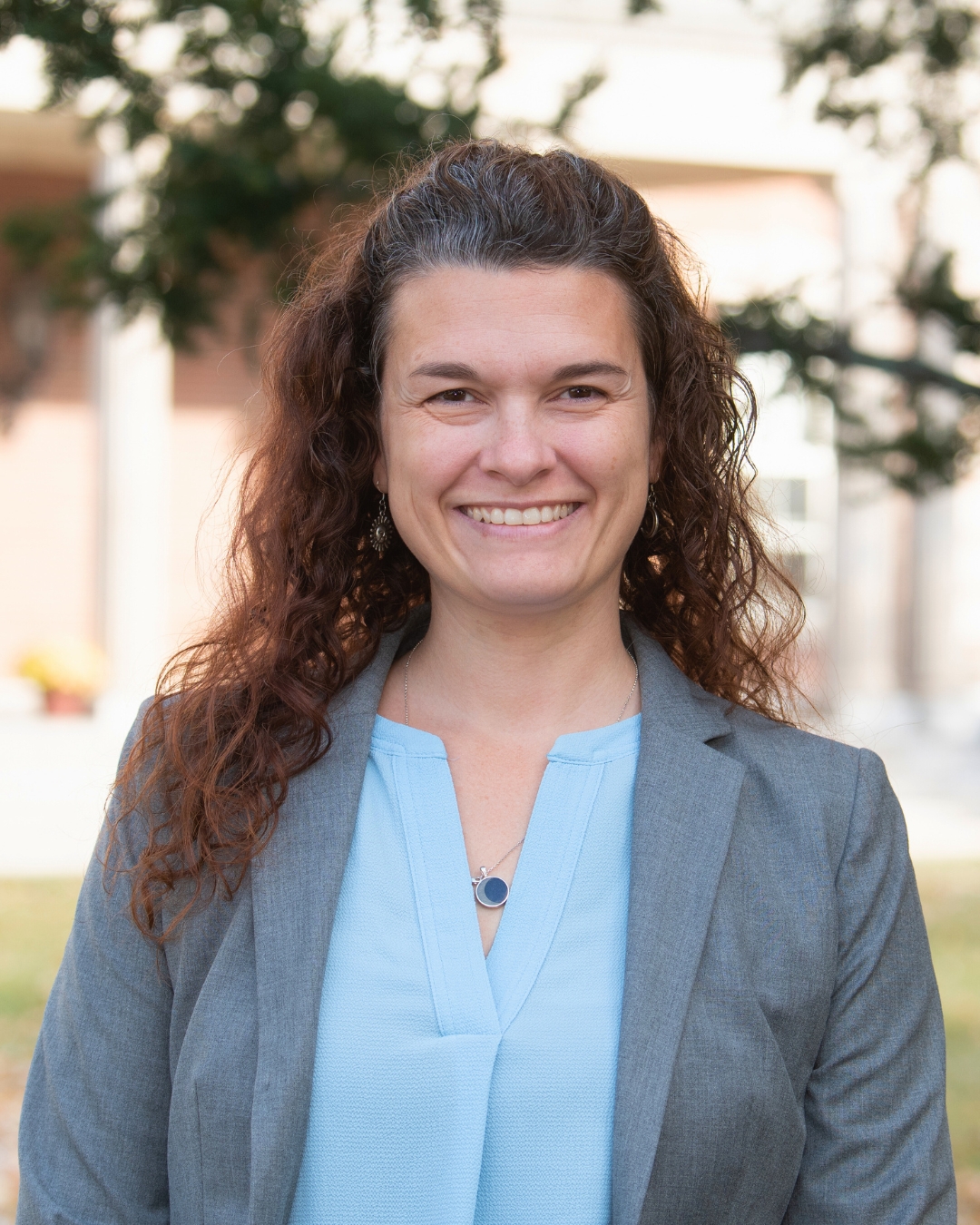 portrait of a woman outside. she wears a gray blazer.