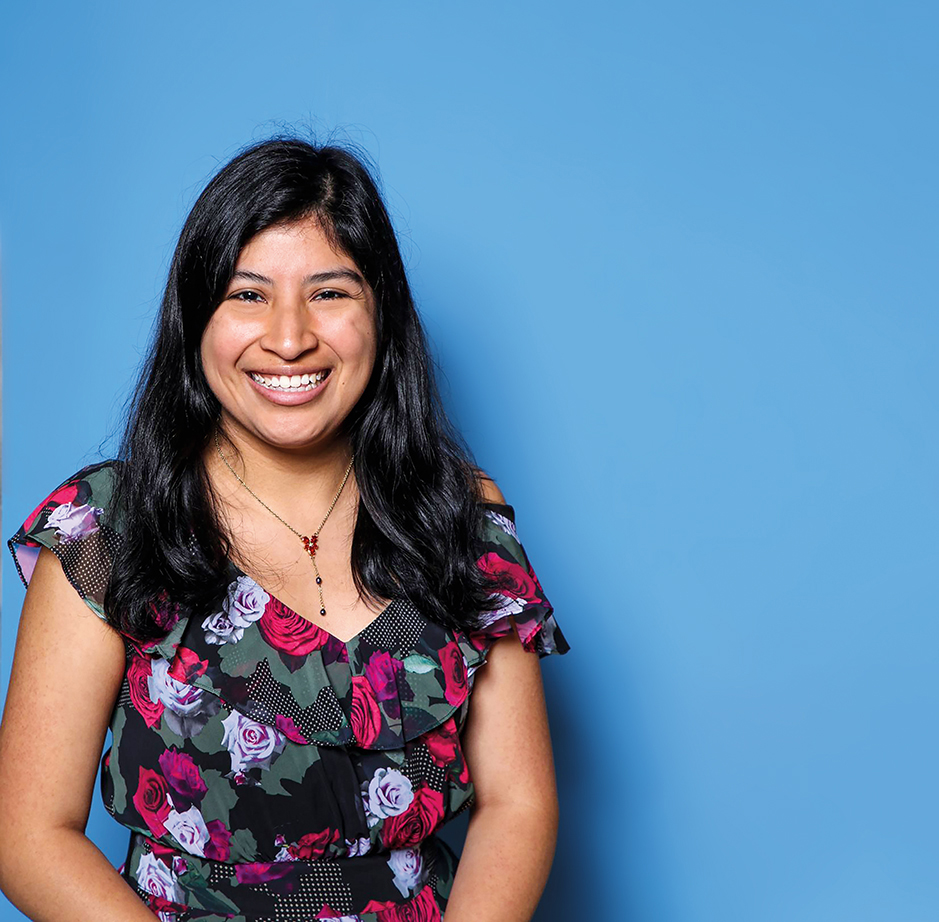 Portrait of a woman against a blue photo backdrop.