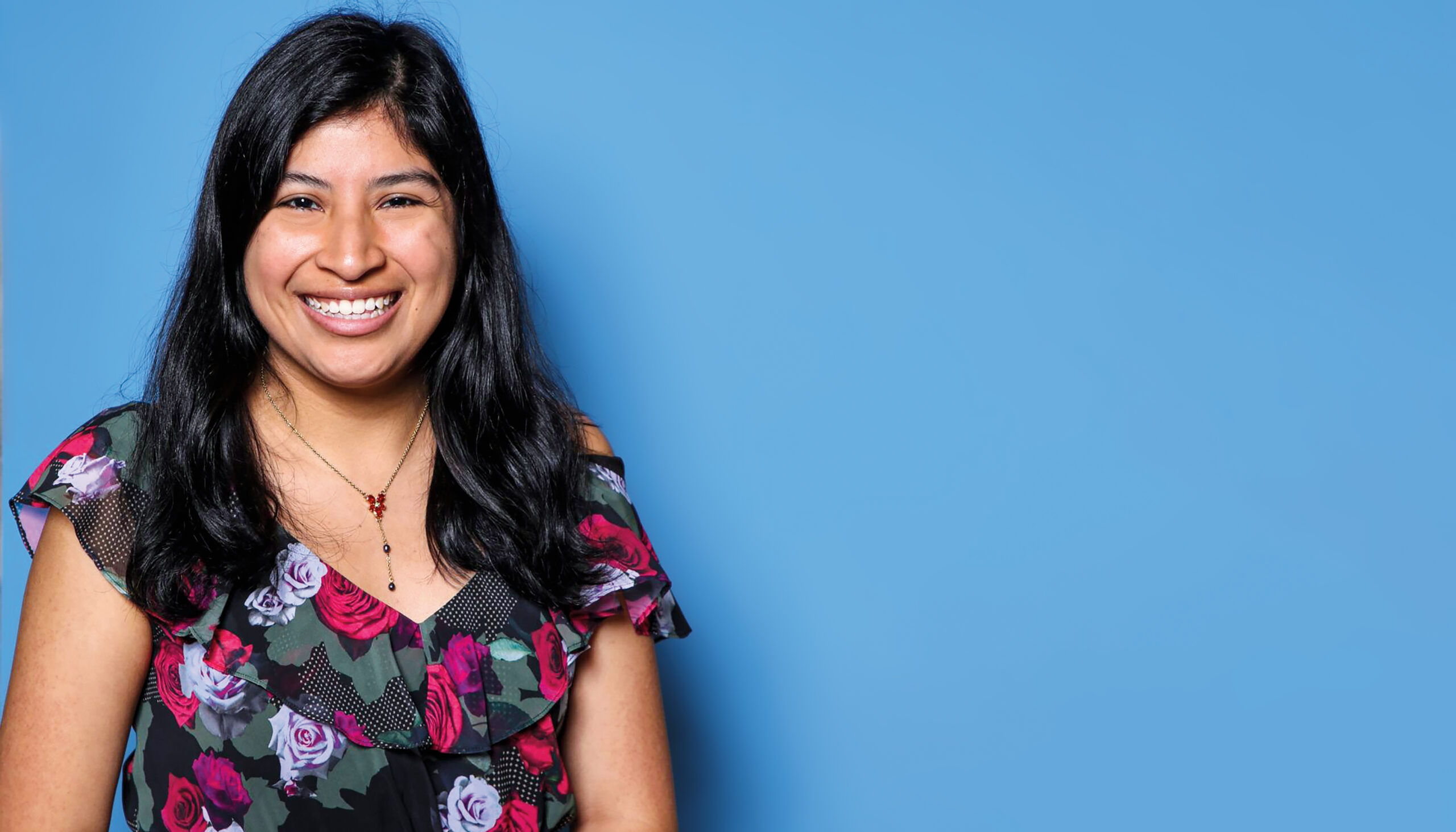 Portrait of a woman against a blue photo backdrop.