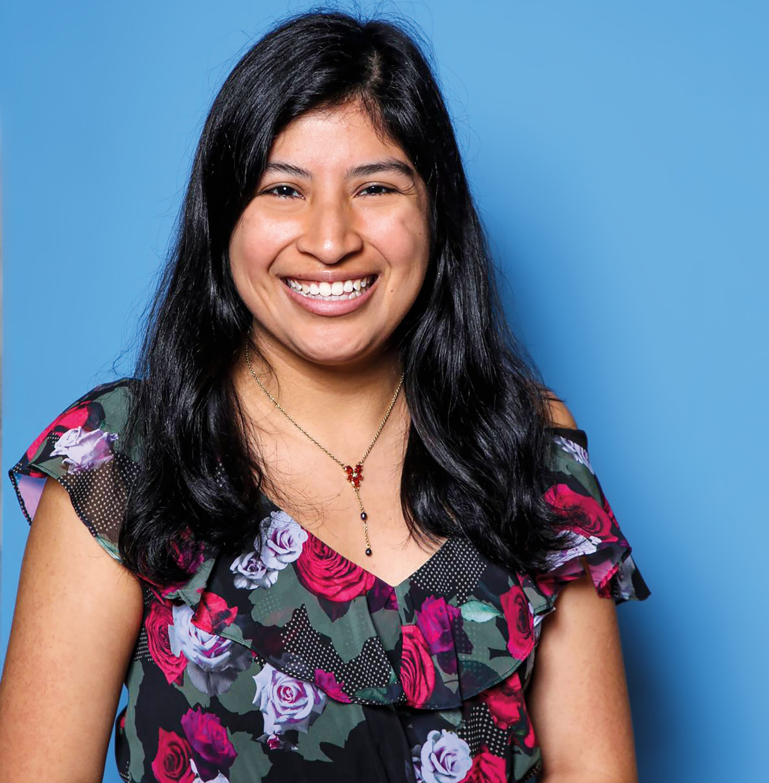 Portrait of a woman against a blue photo backdrop.