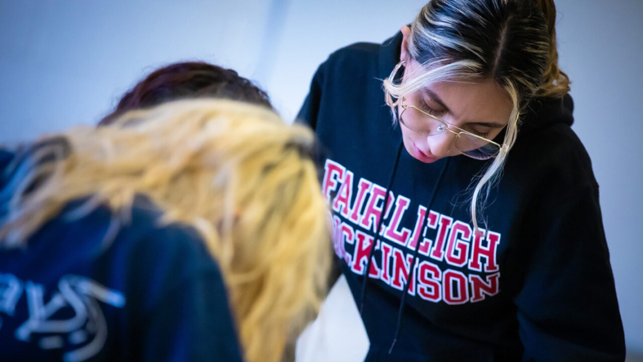 A young woman leans over to help a middle school student.