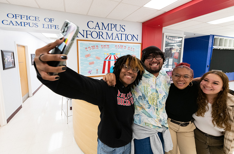 A group of four students snap a selfie in the Student Center at the Florham Campus.