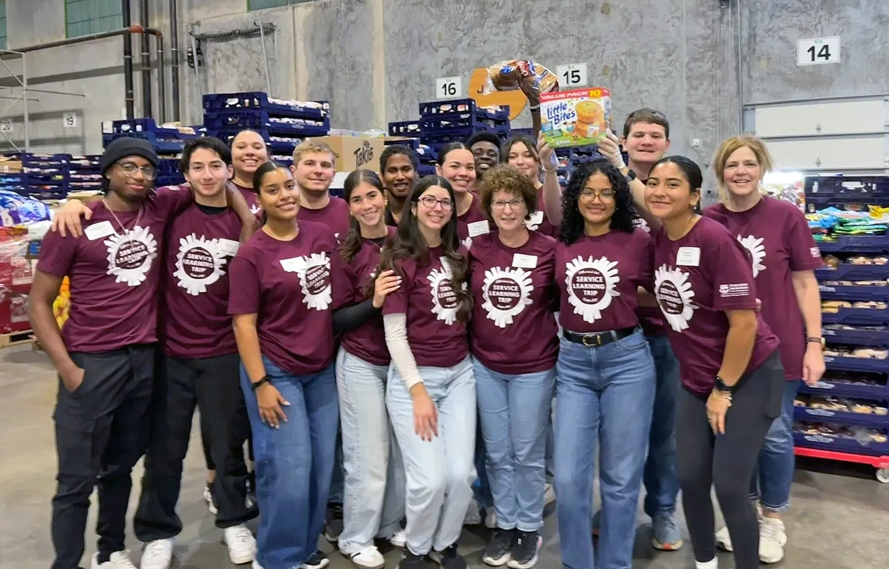 A group of business students in matching t-shirts pose for a group photo.