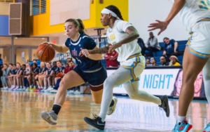 basketball players on a court. one dribbles away from the defending team.